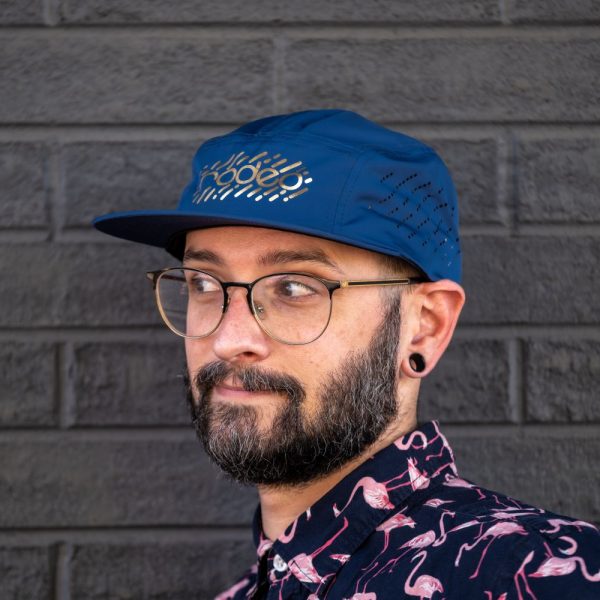 Rodeo Labs 5 panel hat. Blue cap with gold foil logo. Hat has vent holes on the side panels.