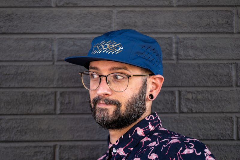 Rodeo Labs 5 panel hat. Blue cap with gold foil logo. Hat has vent holes on the side panels.