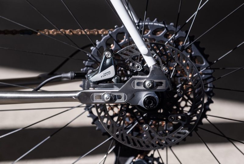 Sliding dropouts on titanium gravel bike frame. The chainstays are cerakoted stormtrooper white and the brakes are Sram Force.